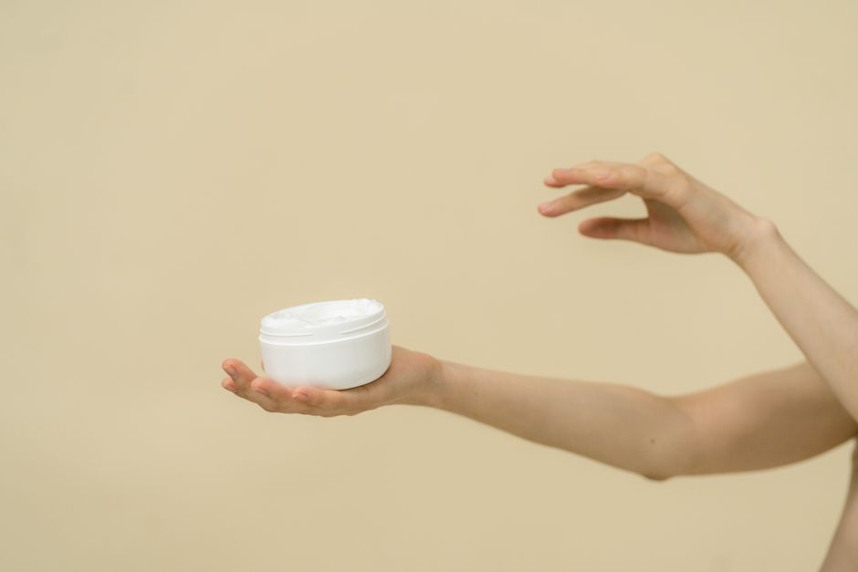 Minimalist image of hands holding a cosmetic jar, emphasizing skincare and beauty.