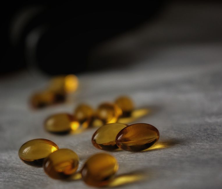 Close-up of golden soft gel capsules with a dark blurred background.