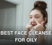 A young woman applies skincare in front of a bathroom mirror, focusing on facial care.