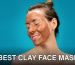 A woman smiles while applying a clay mud mask for skincare treatment.