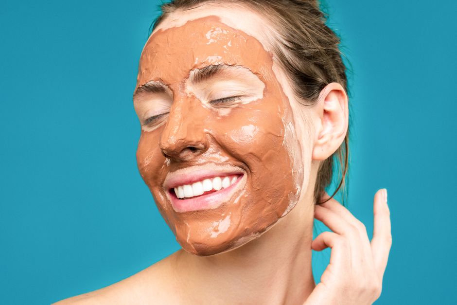A joyful woman with a clay mud mask, epitomizing skincare and self-care.