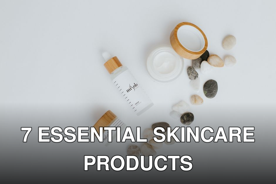 A flat lay of skincare bottles and jars with stones on a white background.