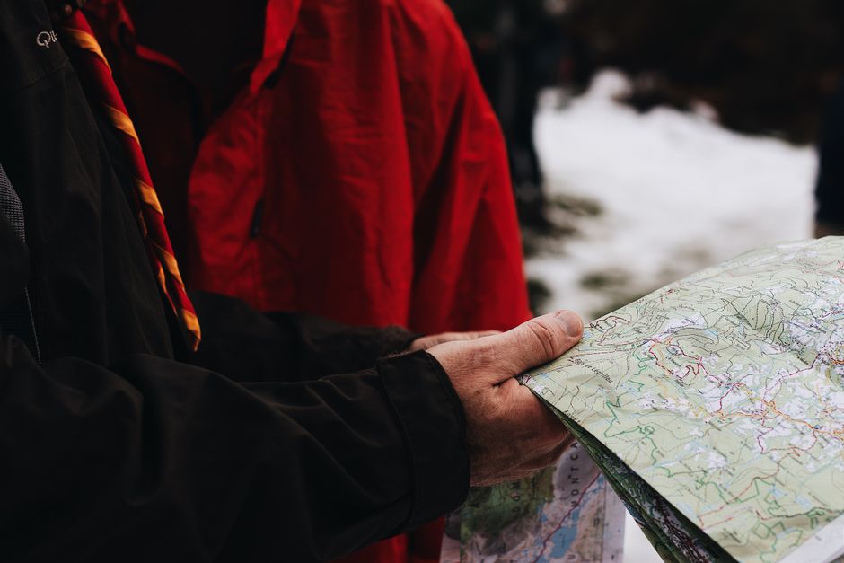 Adult man in winter clothes examining a map outdoors. Great for travel and adventure themes.