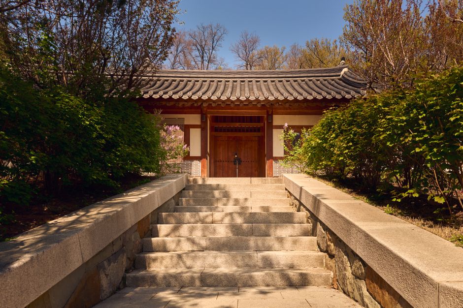 Steps leading to a traditional Korean gate, surrounded by lush spring foliage.