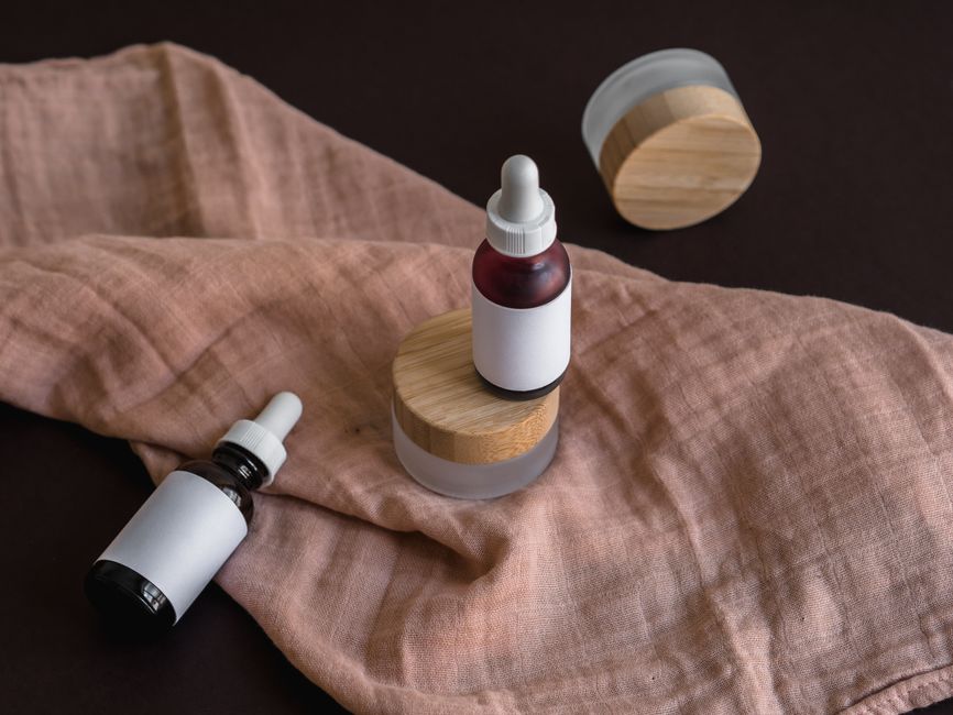 Stylish mockup of glass dropper bottles and containers on a textile background, perfect for branding.