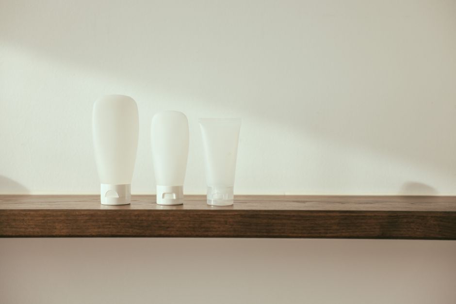 Minimalist product display with white bottles on a wooden shelf for branding mockup.