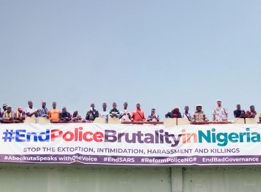 A demonstration against police brutality in Nigeria with people holding a large banner on a bridge.