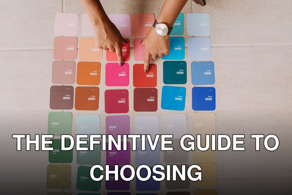 Top view of hands pointing at various color palette cards on a table, showcasing diverse options.