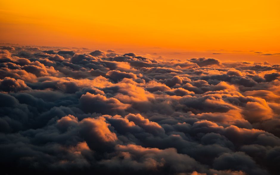 A breathtaking aerial view of clouds illuminated by a vivid sunset sky.
