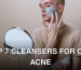 Young man applying clay mask for skincare routine indoors with a mirror.